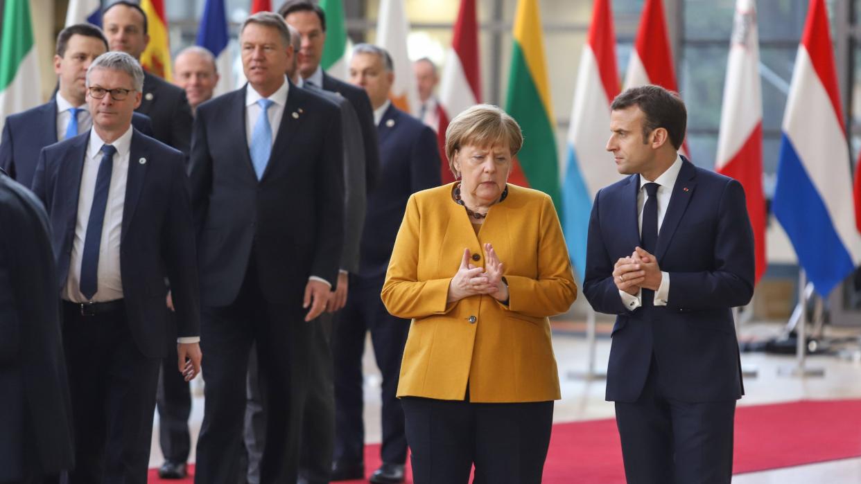 Bundeskanzlerin Angela Merkel und der Französische Präsident Emmanuel Macron sprechen zu zweit beim Verlassen des Ratsgebäudes in Brüssel