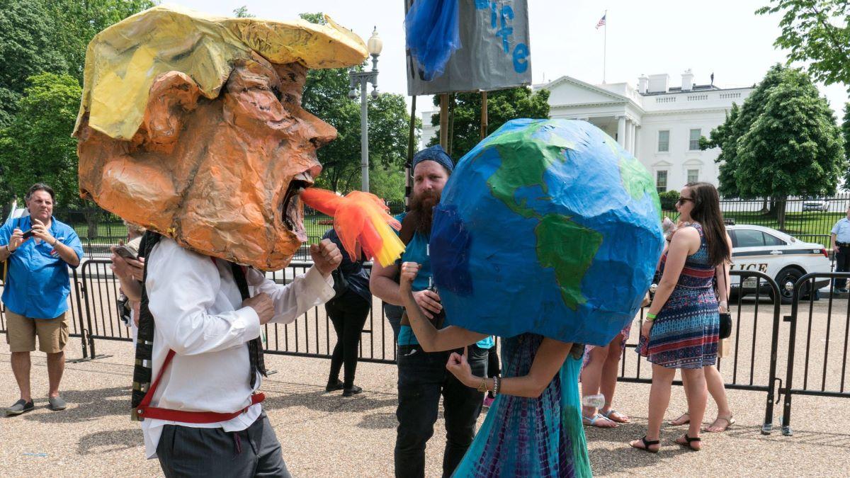 Paper mache heads of US President Donald Trump, and the planet Earth pretend to fight in front of the White House
