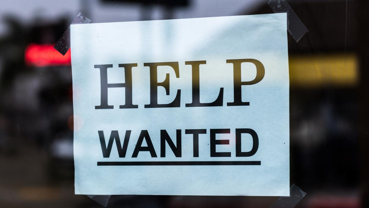 Photo of a help wanted sign posted in a window