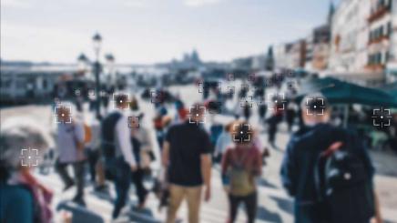 Bild: Eine verschwommene Menschenmenge durch den Sucher einer Kamera mit Gesichtserkennung gesehen