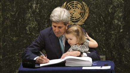 Bild: US-Außenminister John Kerry unterzeichnet das Pariser Klima-Abkommen mit seiner Enkelin auf dem Arm.