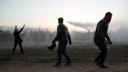 A Greek fire fighter uses a water cannon as migrants gather on the Turkish-Greek border near Turkey's Pazarkule border crossing with Greece's Kastanies, in Edirne
