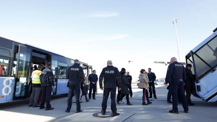 Polizei bewacht Abschiebung von Migranten am Flughafen München.