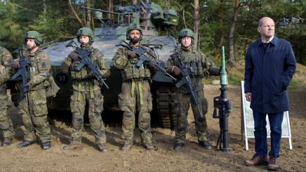 German Chancellor Olaf Scholz stands with German soldiers in front of a Marder vehicle during a visit to a military base of the German army Bundeswehr in Bergen, Germany, October 17, 2022.