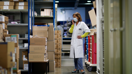 Bild: Eine Apothekerin steht in einem Lager und telefoniert