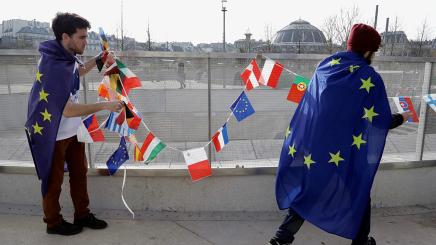 Foto von zwei Menschen mit Europaflaggen und Flaggen der Mitgliedstaaten