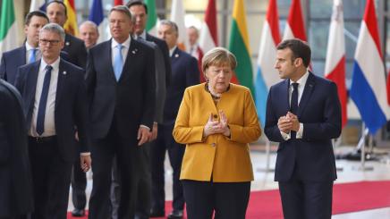 Bundeskanzlerin Angela Merkel und der Französische Präsident Emmanuel Macron sprechen zu zweit beim Verlassen des Ratsgebäudes in Brüssel