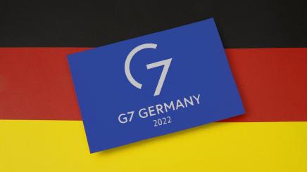 Auf einer Deutschlandfahne liegt das Logo der G7.