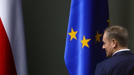 Donald Tusk in front of Flags of Poland and the EU