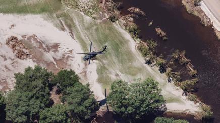 A low-flying Blackhawk helicopter performs a search of the areas along on the Guadalupe River near Camp Mystic where campers are still missing in Hunt on Tuesday, July 8, 2025.