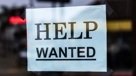 Photo of a help wanted sign posted in a window